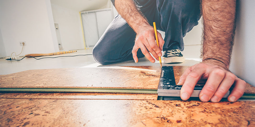 Man measuring a floor with a pencil and tool