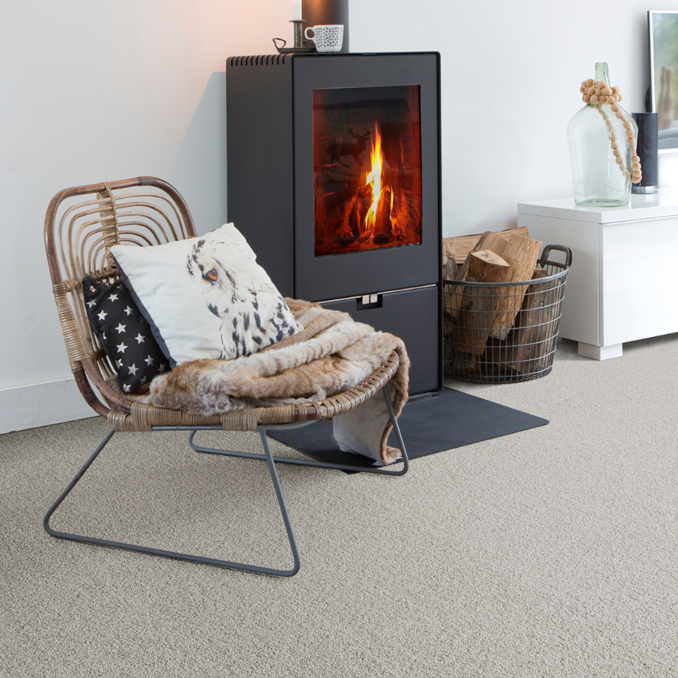 Severus saxony carpet in colour 91 Grey pearl in a lounge with a fireplace and chair