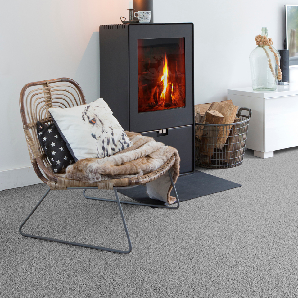 Severus saxony carpet in colour 96 Smoke grey in a lounge with a fireplace and chair