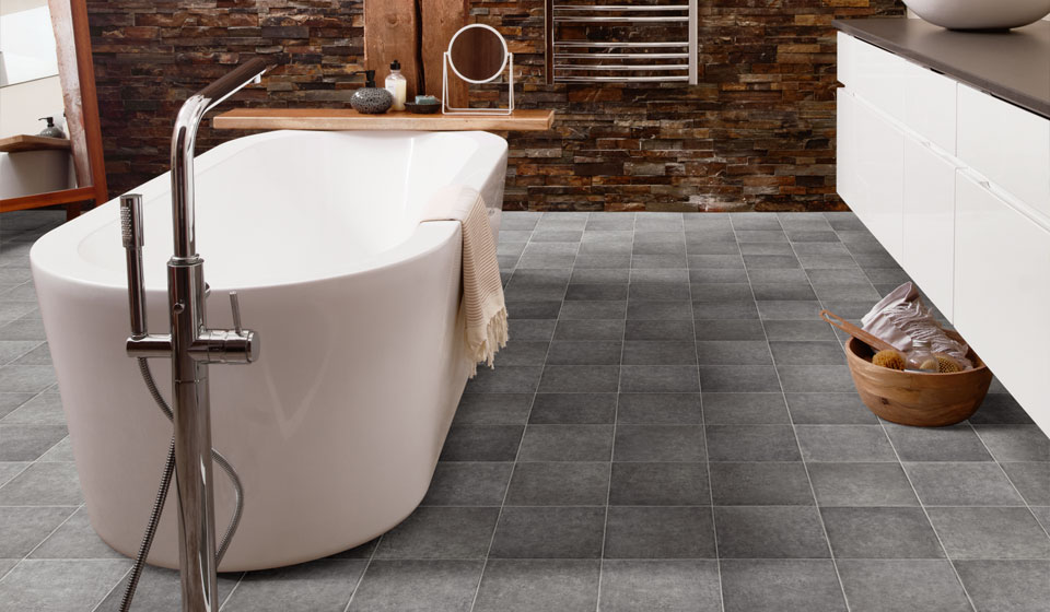 Freestanding bath in bathroom with grey tile effect vinyl flooring